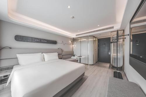 a bedroom with a large white bed and a table at Atour Light Hotel Hangzhou Xiasha in Hangzhou