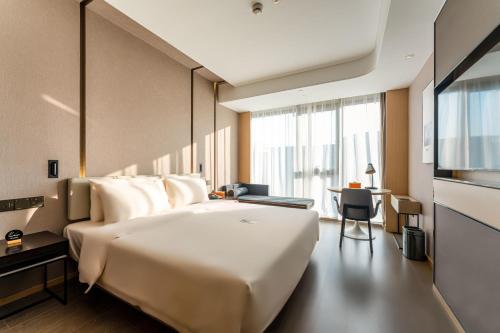 a bedroom with a large white bed and a desk at Atour Hotel Beijing Dahongmen Yintai in Beijing