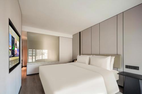 a bedroom with a white bed and a tv at Atour X Hotel Xiamen SM Plaza District Government in Xiamen