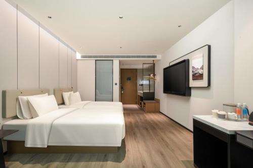 a bedroom with a large white bed and a television at Atour Hotel Quanzhou Jinjiang Sunshine Plaza in Jinjiang