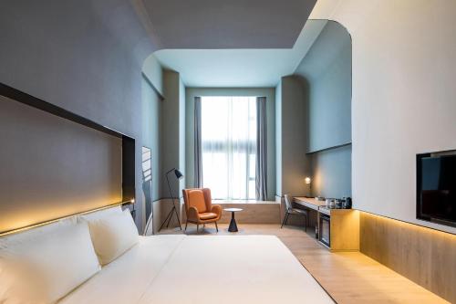 上海市にあるAtour S Hotel Shanghai Hongqiao Center Aegeanのベッドとデスクが備わるホテルルームです。