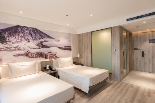 a hotel room with two beds and a painting on the wall at Atour Hotel Harbin Songbei Ice and Snow World in Harbin