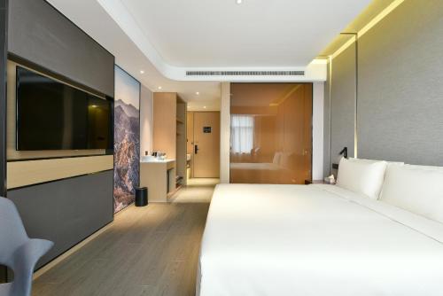 Atour Hotel Beijing Wangjing 798 Art District في بكين: غرفه فندقيه سرير كبير وتلفزيون