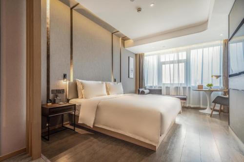 a bedroom with a large white bed and a desk at Atour Hotel Jinan Grand View Garden in Jinan