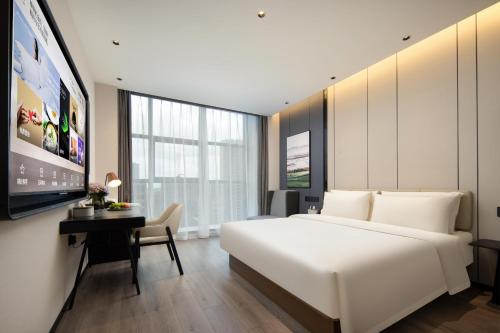 a bedroom with a large white bed and a desk at Atour Hotel Nantong North Street Vientiane City in Nantong