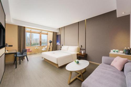 a hotel room with a bed and a couch at Atour S Hotel Xinghai Square in Dalian