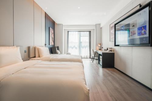 a hotel room with three beds and a flat screen tv at Atour Hotel Chengdu East Station Greenland 468 Center in Chengdu