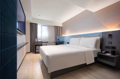 a bedroom with a large white bed and a television at Atour Light Hotel Wuhan Jiangtan Jianghan Road Pedestrian Street in Wuhan