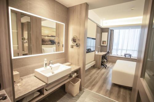 a bathroom with a sink and a large mirror at Atour Hotel Yantai Golden Beach in Yantai