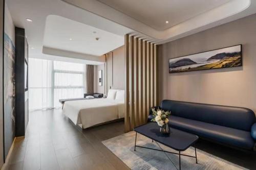 pokój hotelowy z łóżkiem i kanapą w obiekcie Atour Hotel Handan New Century w Handan