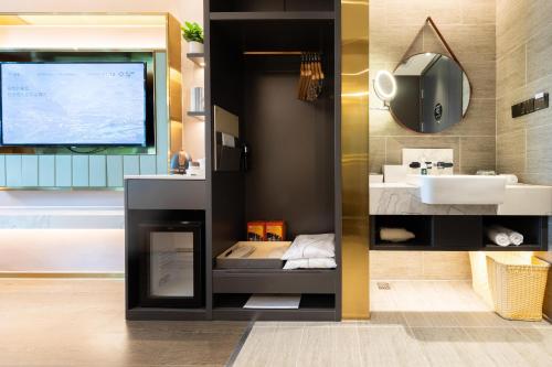 een badkamer met een wastafel en een tv aan de muur bij Atour Light Hotel Shenzhen Nanshan Shenzhen Bay in Shenzhen