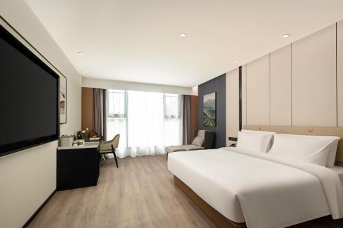 a bedroom with a large white bed and a tv at Atour Hotel Quanzhou Jinjiang Sunshine Plaza in Jinjiang