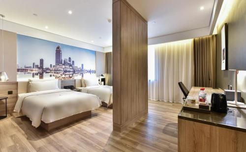 a hotel room with two beds and a desk at Atour Hotel Tianjin Binhai 1st Street in Binhai