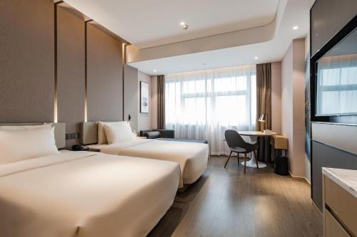 寧波市にあるAtour Hotel Ningbo Gulou Tianyigeのベッド2台とデスクが備わるホテルルームです。