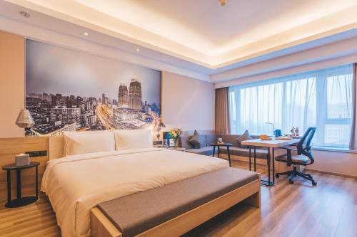 a hotel room with a large bed and a desk at Atour Hotel Shanghai Wujiaochang Dabaishu in Shanghai