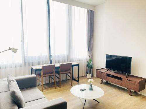 a living room with a couch and a tv and a table at 1BR Siamese素坤逸87 Loft 空中酒吧 高层景观 BTS On Nut in Bangkok