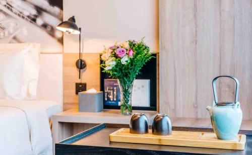 a bedroom with a table with a vase of flowers at Atour Hotel Shanghai Wujiaochang Dabaishu in Shanghai