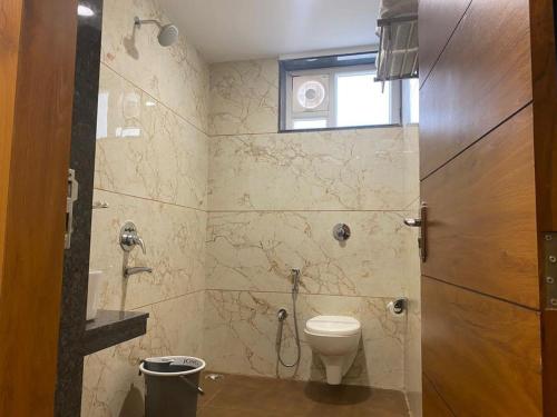 a bathroom with a toilet and a shower with a window at Hotel Heera Residency in Bhopal