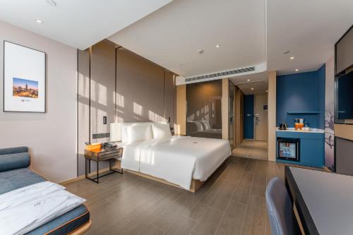 a bedroom with a large white bed and a kitchen at Atour Hotel Changzhou Wujin Science and Education City in Changzhou