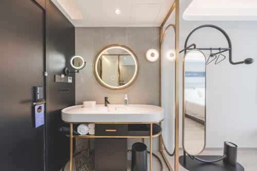 baño con lavabo, espejo y cama en Atour Light Hotel Hangzhou Xiasha, en Hangzhou