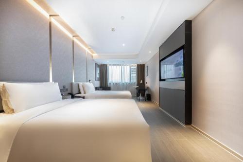 a hotel room with two beds and a flat screen tv at Atour Hotel Hangzhou Wulin Plaza Baochu Road in Hangzhou