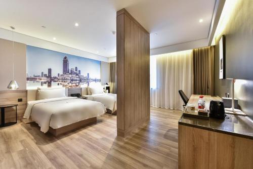 a hotel room with two beds and a television at Atour Hotel Tianjin Binhai 1st Street in Binhai