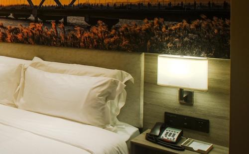 a hotel room with a bed with a lamp and a phone at Atour Hotel Qinhuangdao Xiangxi Sea in Qinhuangdao