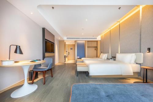 昆明市にあるAtour Hotel Kunming Nanyue Cityのベッドとデスクが備わるホテルルームです。