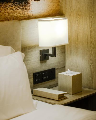a bed with a lamp and a box on a table at Atour Hotel Qinhuangdao Xiangxi Sea in Qinhuangdao