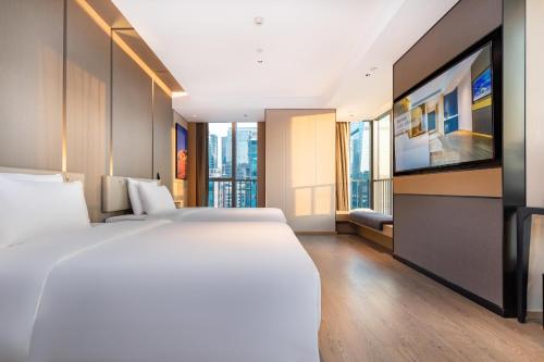 Un dormitorio con una cama grande y un televisor de pantalla plana. en Atour Hotel Shenzhen Futian Xiangmi Lake, en Shenzhen