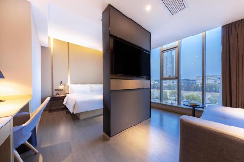 um quarto de hotel com uma cama e uma televisão de ecrã plano em Atour Hotel Ningbo Sanjiangkou Bund Book City em Ningbo