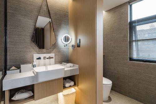 a bathroom with a sink and a mirror and a toilet at Atour Hotel Fuzhou Wusi Road Hot Spring Park in Fuzhou