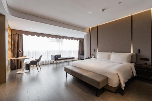 福州福州五四路温泉公园亚朵酒店的酒店客房带一张大床以及一张桌子和椅子。