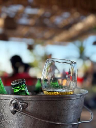 a glass and bottles in a metal bucket at Espetacular Casa de Charme em São Miguel do Gostoso - Salou in São Miguel do Gostoso