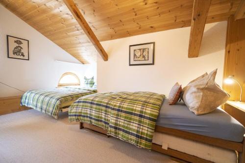 two beds in a room with wooden ceilings at Chasa Rontsch Madlaina in Scuol