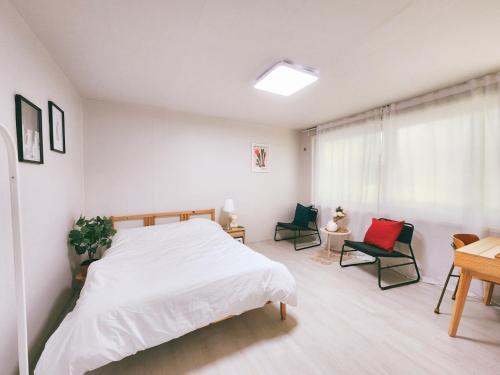 a bedroom with a white bed and two chairs at Raum in Seoul