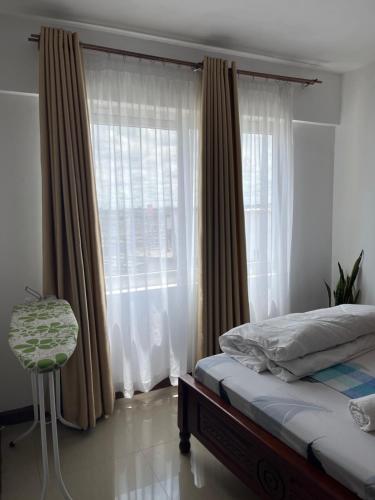 una camera da letto con un letto e una finestra con tende di The Coffee Residences- 3 Bedroom Apartments-4km to JKIA, 7km to CBD a Nairobi