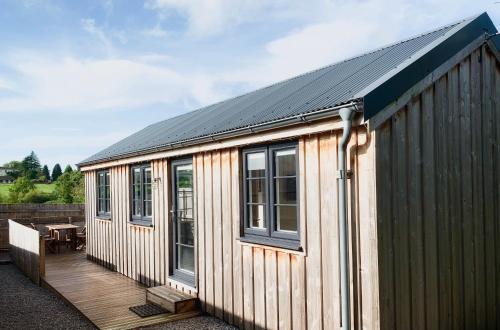a wooden building with a deck and a table at Cosy Cabins without hot tub - Greenway Farm, Drybrook, Forest of Dean in Drybrook