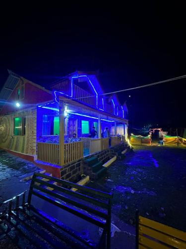 a house lit up in blue and green at night at Crown Bliss - Riverside Luxury Paradise in Kasol