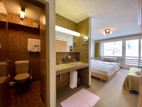 a bathroom with a bed and a sink and a bathroom with a toilet at Hotel Alpina Parpan in Parpan