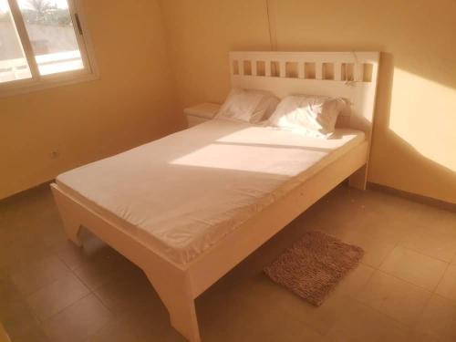 uma cama branca num quarto com uma janela em Chez Manga em Ziguinchor