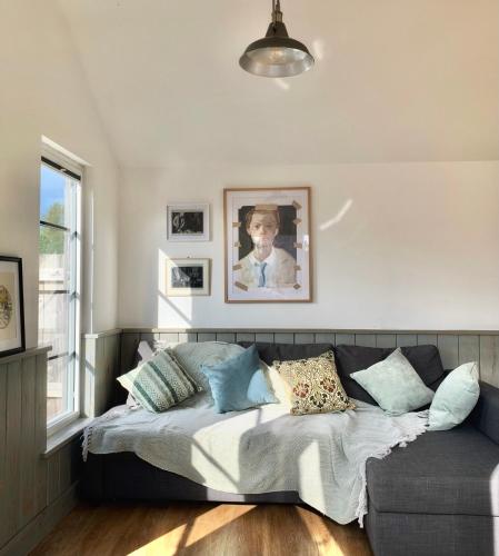 a bedroom with a bed and a couch with pillows at Cosy Cabins without hot tub - Greenway Farm, Drybrook, Forest of Dean in Drybrook