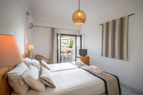 een wit bed in een kamer met een raam bij Heronissos Hotel in Chersonissos