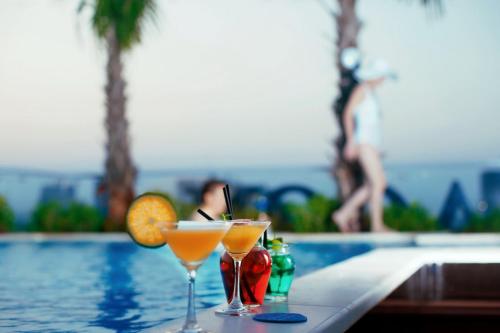 two cocktails sitting on a table next to a swimming pool at Alagon Saigon Hotel & Spa in Ho Chi Minh City