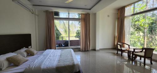 a bedroom with a bed and a large window at Mazra Retreat, Coorg Kushālnagar in Kushālnagar