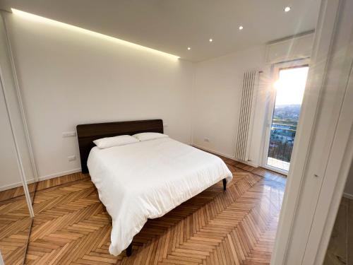 a white bedroom with a large bed and a window at Attici Alba e Tramonto Ospedale e Vista in Brescia