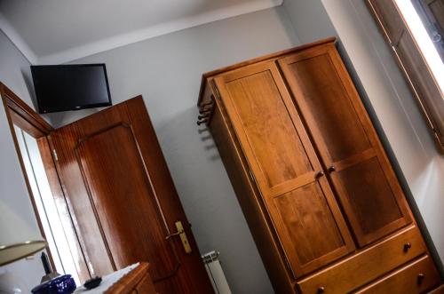 a bedroom with a wooden cabinet and a tv on the wall at Alminhas House in Alapela