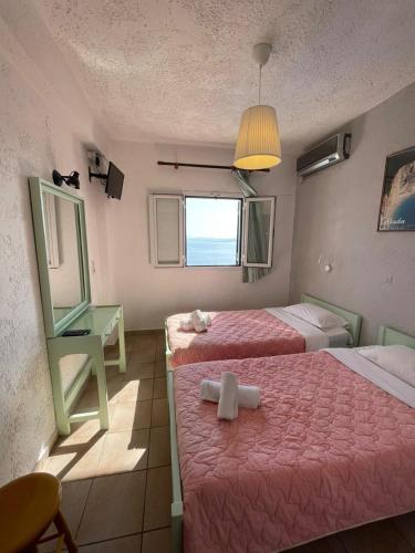 a room with two beds and a mirror and a window at Yannis Apartments Barbati in Barbati