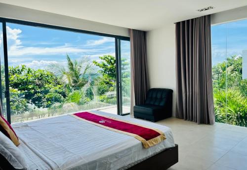 a bedroom with a bed and a chair and a large window at D6 Aria Resort in Vung Tau