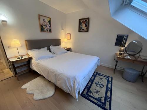 una camera da letto con un letto bianco, due tavoli e una finestra di Villa Omaha a Saint-Laurent-sur-Mer